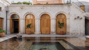 Ein Innenhof mit einem Brunnen, Bögen und Kübelpflanzen.
