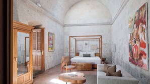 Ein Schlafzimmer mit Himmelbett, Holzmöbeln und einem großen Gemälde an der Wand.