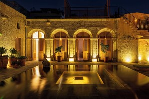 A courtyard with a pool, stone walls, and arched doorways. - Palacio Guaqui (Arequipa)