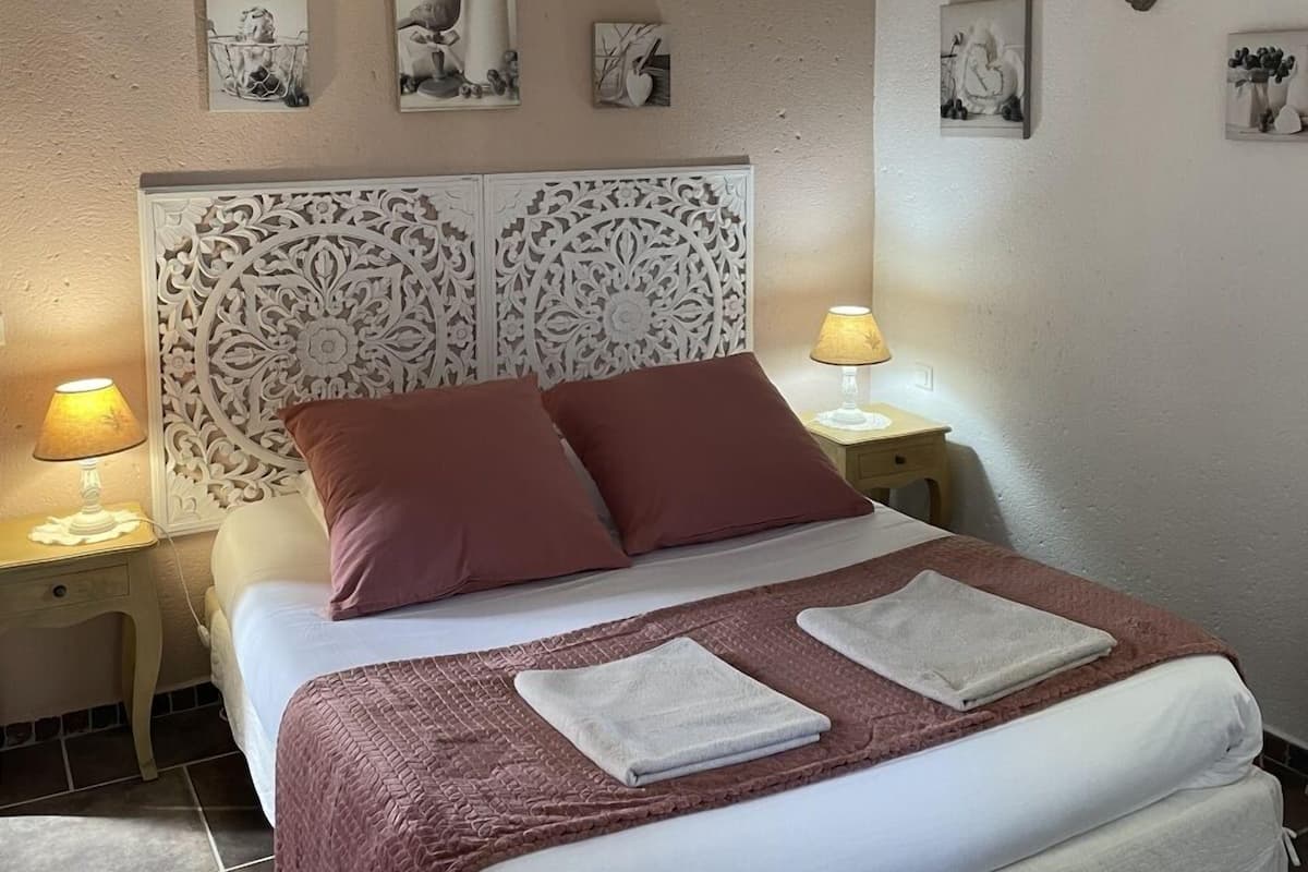 A bedroom with a bed, two nightstands, wall-mounted lamps, and decorative wall art.