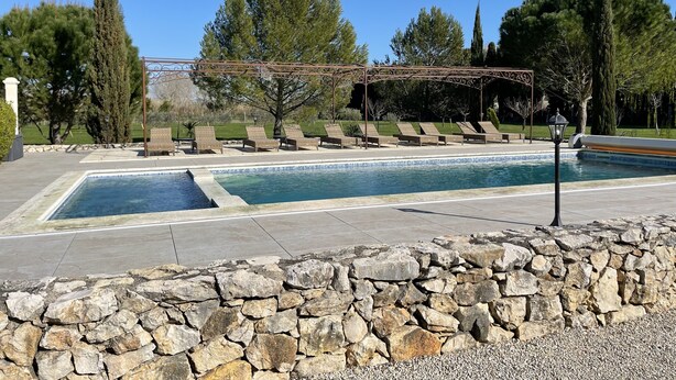 A swimming pool with lounge chairs and a pergola. - Le Mas Des Chutes (Graveson)