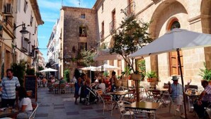A narrow street with outdoor seating areas, stone buildings, and a clear sky. - Casa Solanilla Entre mer et Golf (La Sella)