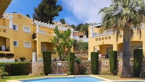 A hotel with two swimming pools, a stone wall, and a palm tree. - Casa Solanilla Entre mer et Golf (La Sella)