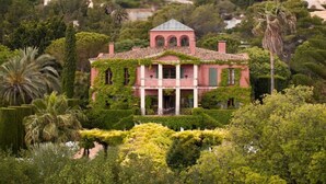 A pink villa with a tiled roof, surrounded by lush greenery and palm trees. - Casa Solanilla Entre mer et Golf (La Sella)