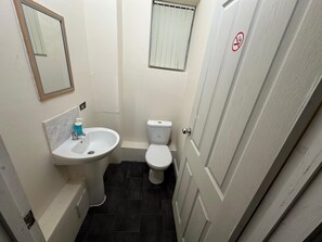 A small bathroom with a sink, toilet, and a mirror. - Macclesfield Lodge (Macclesfield)