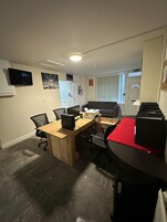 Una sala conferenze con un tavolo in legno, sedie da ufficio nere, una scrivania nera e un tappeto rosso.