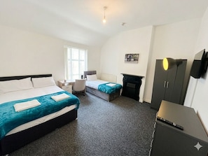 A hotel room with two beds, a desk, a chair, a fireplace, and a TV. - Macclesfield Lodge (Macclesfield)