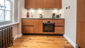 Une cuisine moderne avec des meubles en bois, un four Bosch et une fenêtre donnant sur la ville.