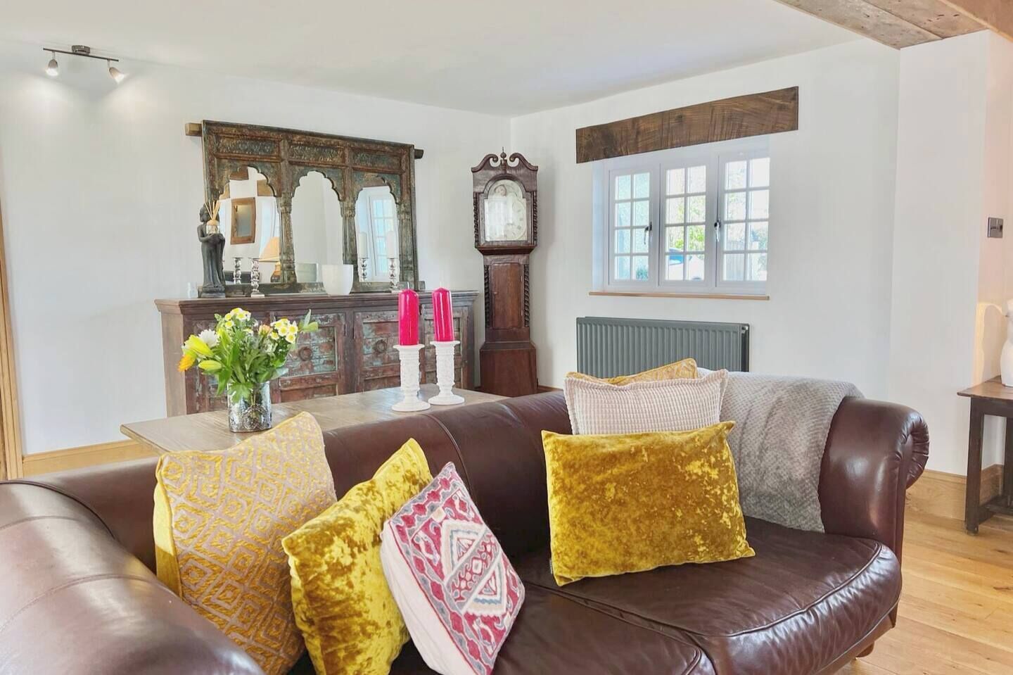 A living room with a brown leather sofa, a wooden cabinet, and a large mirror.