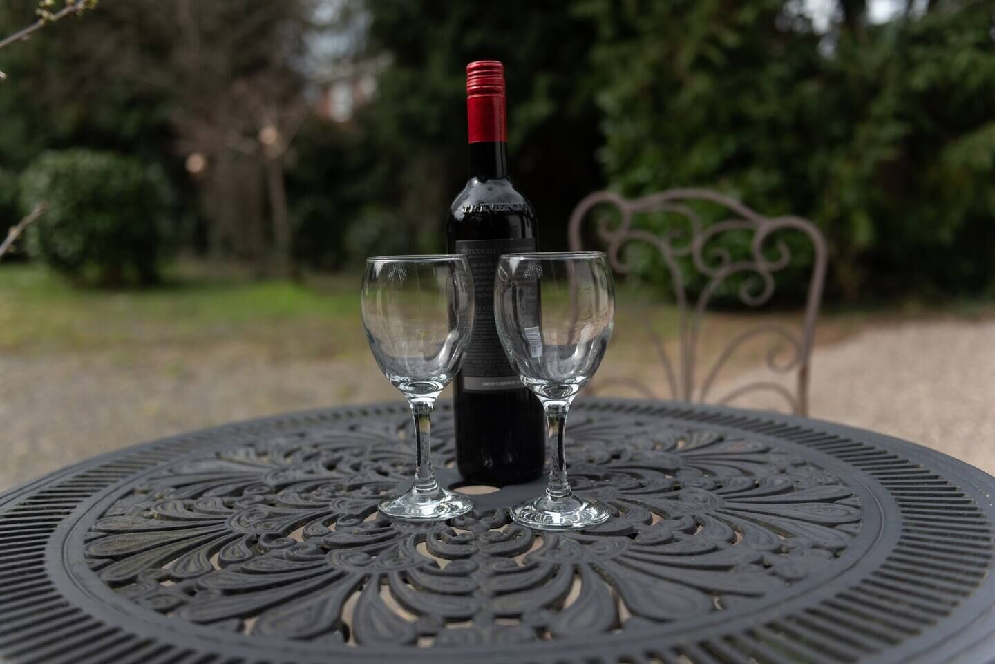 A bottle of wine on a table with two glasses.