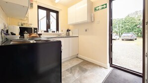 A compact kitchen with a black countertop, white cabinets, and a window with a view of parked cars outside.