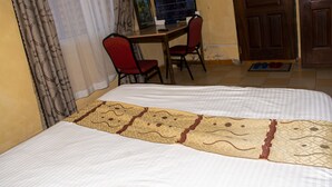 Een slaapkamer met een bed, een bureau met een computer en een stoel.