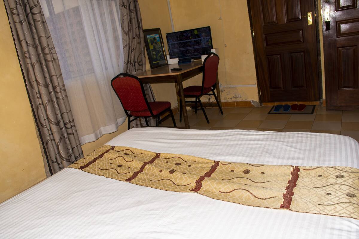 Une chambre à coucher avec un lit, un bureau avec un ordinateur et une chaise.