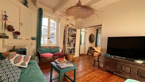 Ein gemütliches Wohnzimmer mit Kamin, Bücherregal, Fernseher und einer Lampenschirm aus Weidwerk.