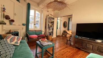 Een gezellige woonkamer met een open haard, een boekenkast, een televisie en een rieten kroonluchter.