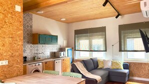 A compact living space with a kitchenette, a dining area, and a seating area with a sofa and cushions. - Apartamento con Baño Adaptado (Astorga)