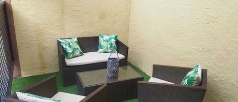A small patio area with a sofa and two armchairs, a coffee table, and a decorative lantern.