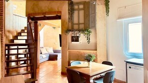Ein Essbereich mit Holztisch und Stühlen, einer Treppe und einem fenster mit Vorhängen.