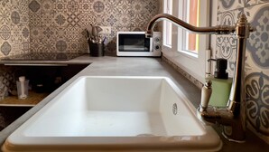 A kitchen with a white sink, a stainless steel faucet, a microwave, and patterned backsplash tiles. - Espacioso Apartamento con Bañera (Astorga)