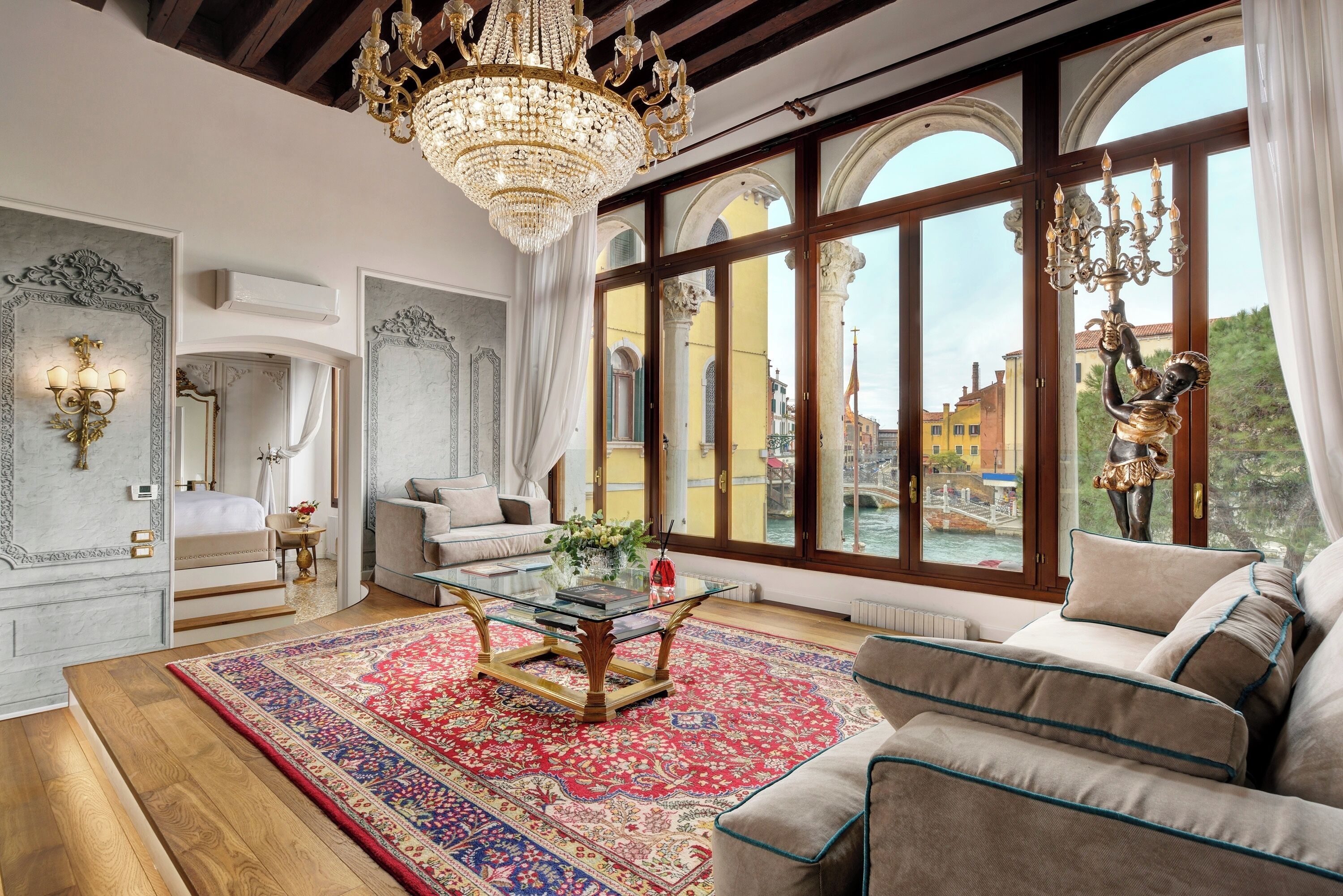 Una habitación amplia con un gran ventanal, un candelabro, un sofá y una mesa de centro.