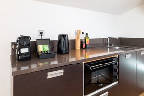 A compact kitchenette with a coffee maker, a kettle, a bottle of olive oil, and a dish soap.