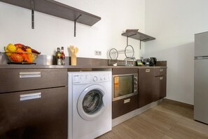 Eine moderne Küche mit integriertem Wasch- und Trockner, Holzschränken und einer Obstschale auf der Arbeitsplatte.