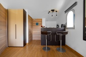 Eine kompakte Küche mit einer zentralen Kochinsel, zwei Barhocker und einem Holzschrank.