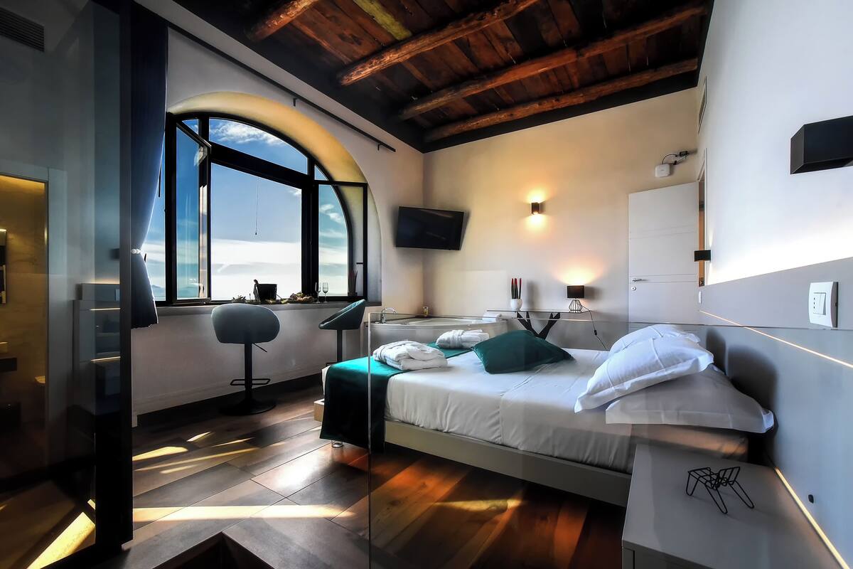 Una habitació d'hotel moderna amb llit, escriptori, cadira, televisió i finestra amb vista.