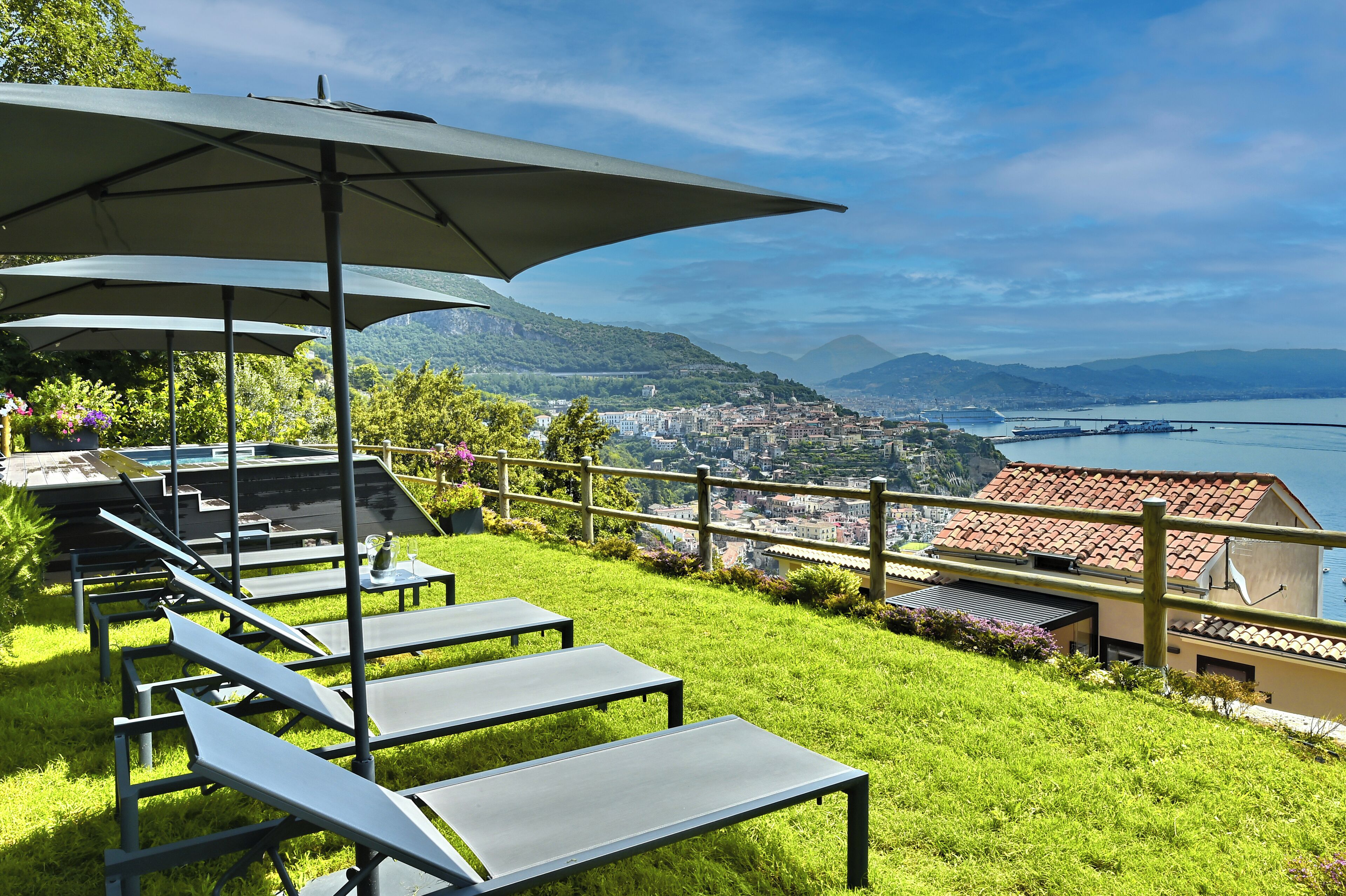 A terrace with outdoor seating and a view of a city and mountains.