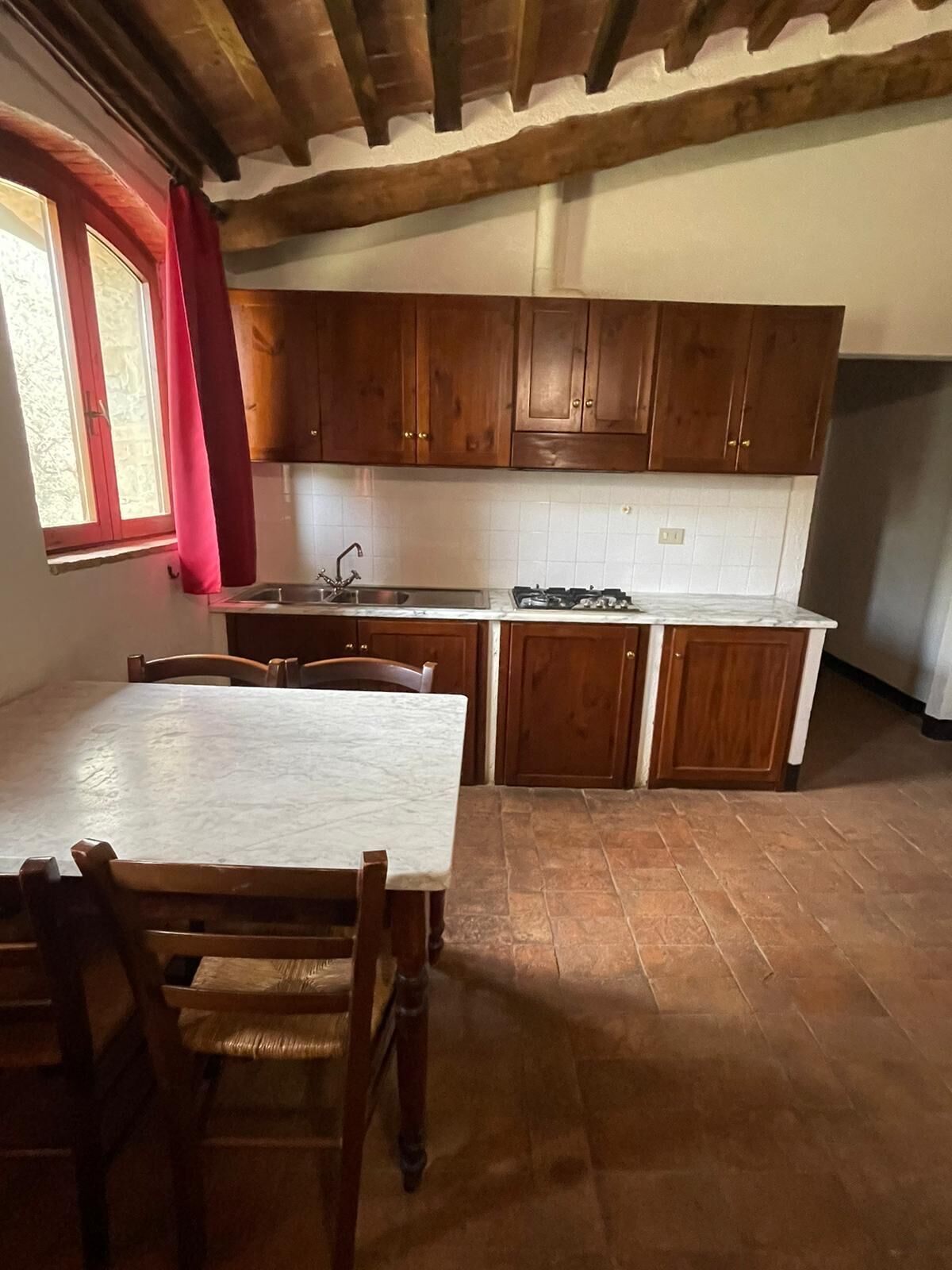 A kitchen with wooden cabinets, a white countertop, and a dining table with chairs.