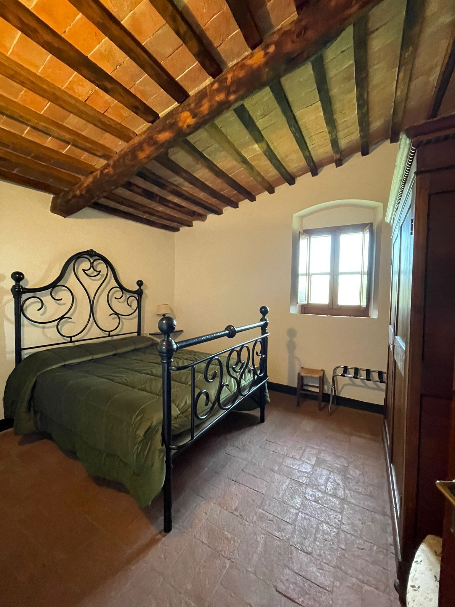 Un dormitorio con cama, ventana, una mesita y una puerta.