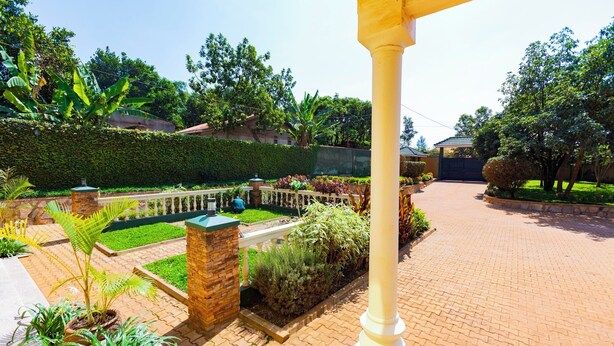 A well-maintained garden with a paved walkway, a stone wall, and various plants.