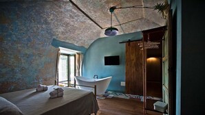 Un dormitorio con una cama grande, una bañera y suelo de madera.