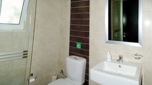 A bathroom with a toilet, sink, and mirror. - Cozy Studio with Swimming Pool Near the Sea (Chania)