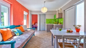 A bright room with a sofa, a dining table, and a kitchen area.