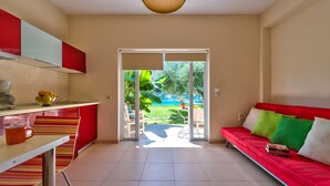 A modern apartment with a kitchen, dining area, and a red sofa with cushions. - Cozy Apartment with Swimming Pool Near the Sea (Chania)