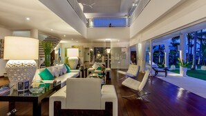 A spacious, modern living area with a high ceiling, a balcony, and a view of palm trees. - Coconut Palms and Endless Blue Skies! (Candidasa)