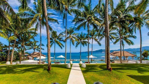 A pathway leading to a beach with palm trees and umbrellas, overlooking the sea. - Coconut Palms and Endless Blue Skies! (Candidasa)