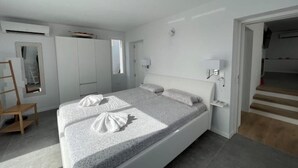 Ein modernes Schlafzimmer mit einem großen Bett, einem Kleiderschrank, einem Schreibtisch und einem Sessel.