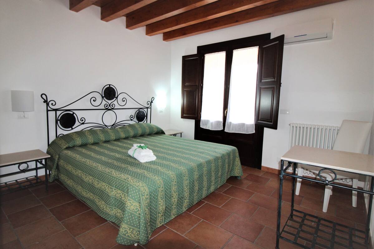 A bedroom with a bed, a table, and a chair.