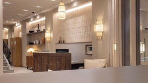 A modern interior with a wooden reception desk, a staircase, and a wall-mounted light fixture. - Sonder Yelo Lumiere (Cannes)