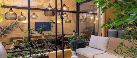 A modern indoor patio with a sofa, table, and hanging lights.