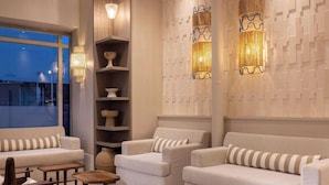 A modern lounge with sofas, wooden side tables, and decorative wall sconces. - Sonder Yelo Lumiere (Cannes)