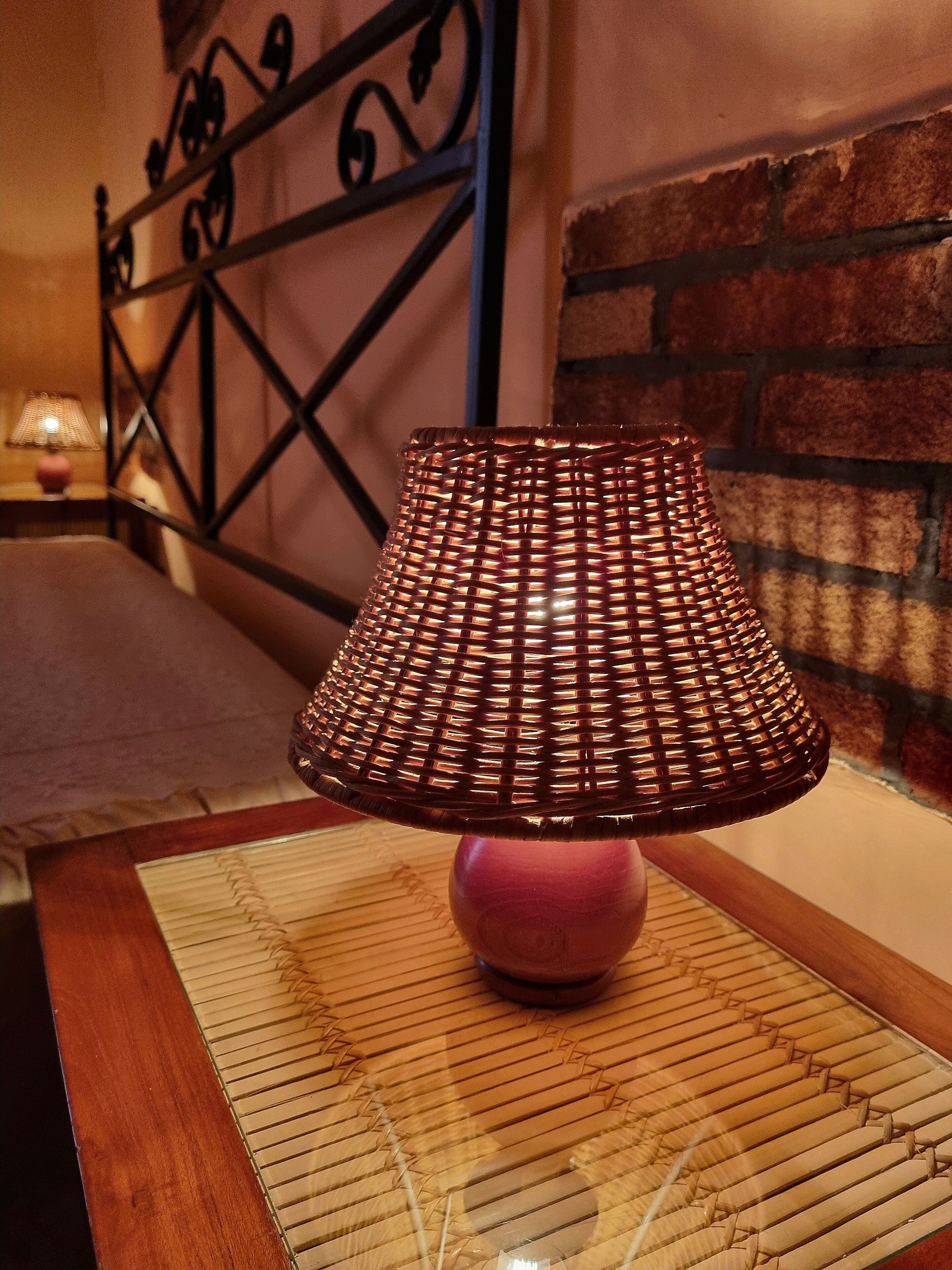 A woven lamp on a wooden table with a patterned table runner.