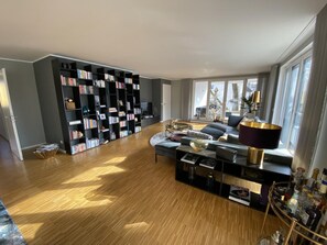 Ein geräumiges Wohnzimmer mit einem großen, schwarzen Bücherregal, einem bequemen Sofa und einem Couchtisch.