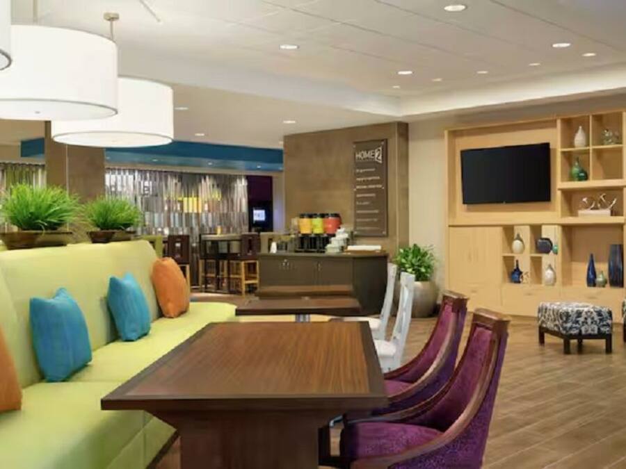 Um lobby moderno de hotel com área de estar, bar e televisão.