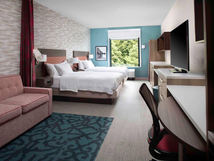 Una habitación de hotel con una cama, un escritorio, una silla, un sofá y un televisor.