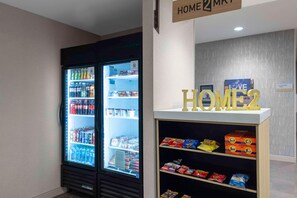 Máquina expendedora con aperitivos y un refrigerador lleno de bebidas.