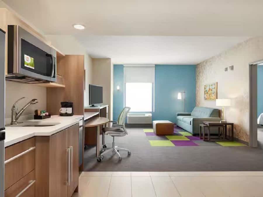 Een moderne hotelkamer met een kitchenette, een bank, een bureau en een televisie.