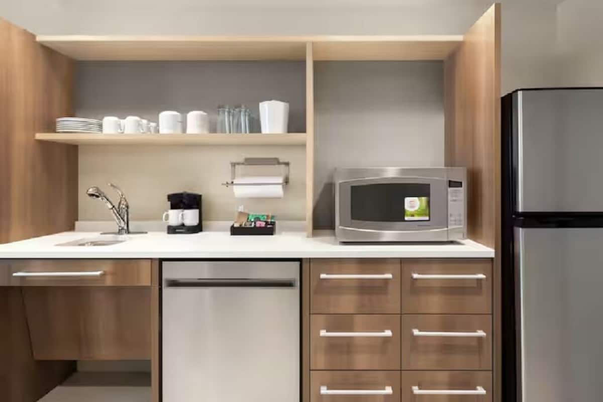 A modern kitchen with a stainless steel refrigerator, a microwave, and a coffee maker on the counter.